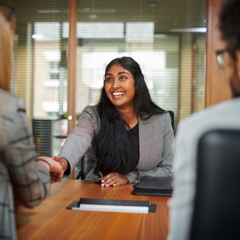 picture of a smiling woman shaking hands during a job interview